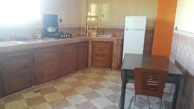 a kitchen with a table and a white refrigerator at Bassatine appartement in Meknès