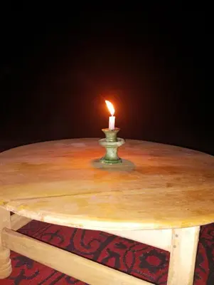 a candle sitting on top of a wooden table at voyageur m'hamid Ghislaine in Tâlhâ