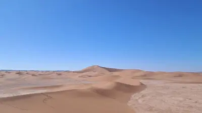a desert with sand dunes and a blue sky at voyageur m'hamid Ghislaine in Tâlhâ