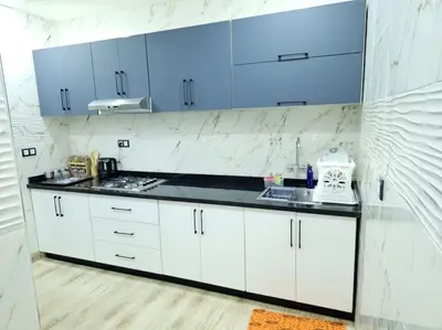 a kitchen with white counters and blue cabinets at Superbe maison près de la gare de train in Fès