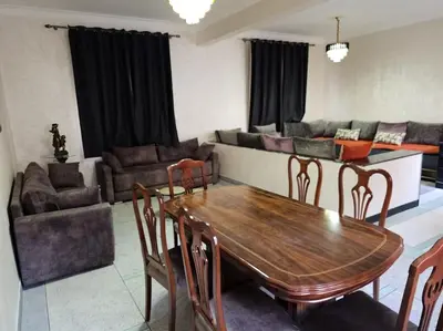 a living room with a wooden table and chairs at Superbe maison près de la gare de train in Fès