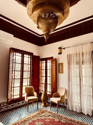 a living room with chairs and a large chandelier at Riad Zawiyat Fes in Fès