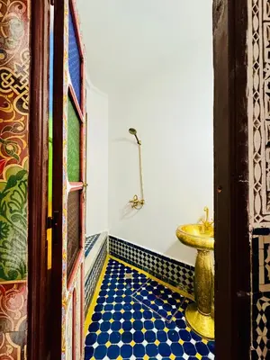 a bathroom with a toilet and a blue tiled floor at Riad Zawiyat Fes in Fès