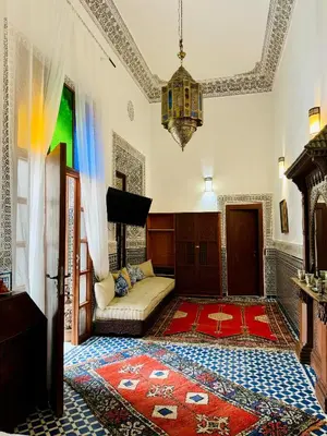 a living room with a couch and a tv at Riad Zawiyat Fes in Fès