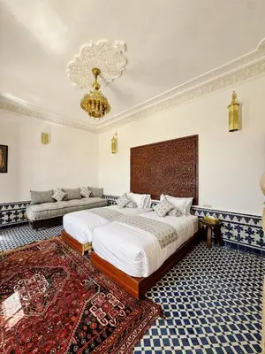 a bedroom with a large bed and a chandelier at Riad Zawiyat Fes in Fès