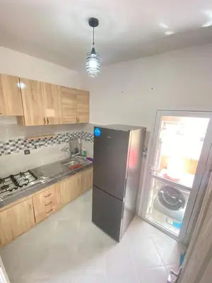 a kitchen with a stainless steel refrigerator and wooden cabinets at طريق صفرو قرب المستشفى الجامعي و قرب مستشفي أكديطال in Fès