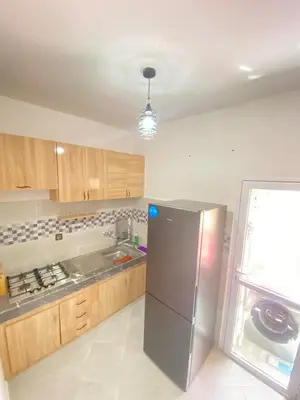 a kitchen with a stainless steel refrigerator and wooden cabinets at طريق صفرو قرب المستشفى الجامعي و قرب مستشفي أكديطال in Fès