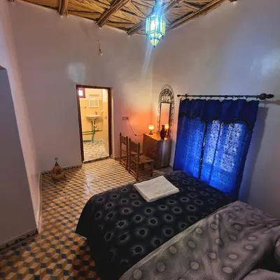 a bedroom with a bed and a table and a mirror at Riad Taourirte in Tinerhir