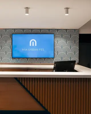 a reception desk with a laptop on a wall at MIA Urban Fès in Fès