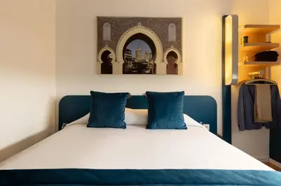 a bedroom with a bed with blue pillows at MIA Urban Fès in Fès