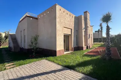a house with a palm tree next to a building at Luxueuse villa contemporaine KIMANU à 20 min de Marrakech in Marrakech