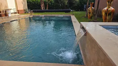 a pool with a water fountain in a yard at Luxueuse villa contemporaine KIMANU à 20 min de Marrakech in Marrakech