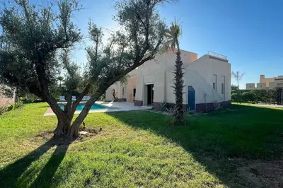 a tree in the grass next to a building at Luxueuse villa contemporaine KIMANU à 20 min de Marrakech in Marrakech
