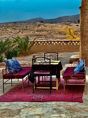 a table and two chairs sitting on a rug at Auberge Dar Lajdoud in Tafraoute Sidi Ali