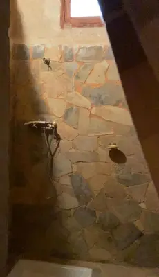 a stone wall with a shower in a room at Maison Chez Lahcen - Akka Nait Sidi - Tissint in Tissint