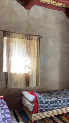 a room with a window with a bed and a curtain at Maison Chez Lahcen - Akka Nait Sidi - Tissint in Tissint