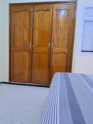 a bedroom with a wooden cabinet and a bed at Appartement Atlas City Center in Fès