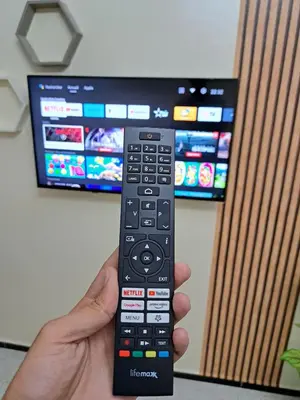 a hand holding a remote control in front of a tv at Appartement Atlas City Center in Fès