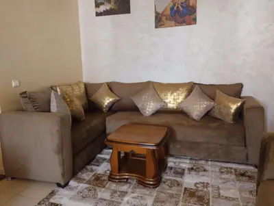 a living room with a brown couch with gold pillows at Maison Samy in Ifrane