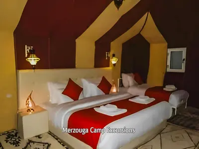 a bedroom with two beds with red and white pillows at Merzouga Camp Excursions in Merzouga