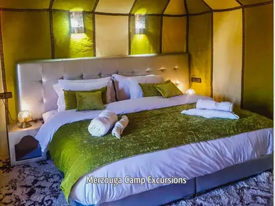 a bedroom with a large bed with towels on it at Merzouga Camp Excursions in Merzouga