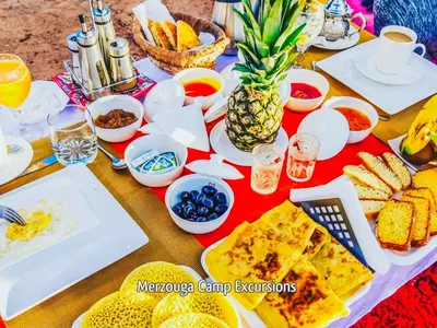 a table topped with plates of food and fruit at Merzouga Camp Excursions in Merzouga