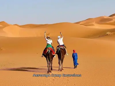 two people riding on a camel in the desert at Merzouga Camp Excursions in Merzouga