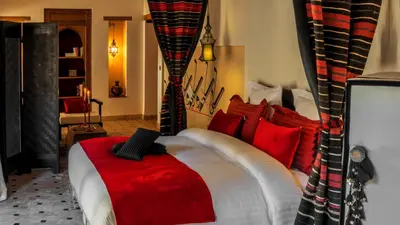 a bedroom with a large bed with red pillows at Karawan Riad in Fès