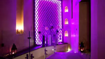 a bathroom with purple lighting and a tub with a window at Karawan Riad in Fès