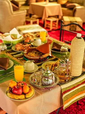 a table topped with plates of food and fruit at Best Luxury Camp in Merzouga