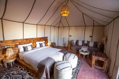 a bedroom in a tent with a bed and a couch at Best Luxury Camp in Merzouga