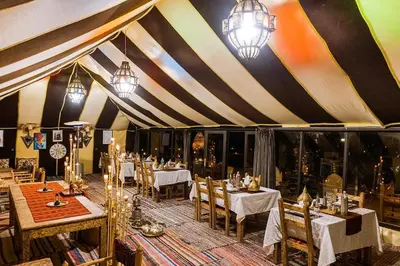 a dining room with tables and chairs in a tent at Best Luxury Camp in Merzouga