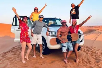 a group of people standing in front of a car in the desert at Best Luxury Camp in Merzouga
