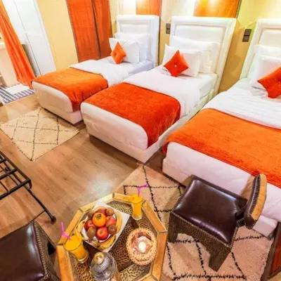 a hotel room with two beds and a tray of fruit at Best Luxury Camp in Merzouga