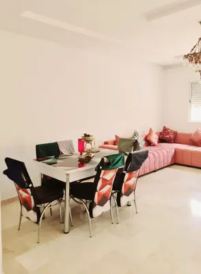 a living room with a table and a pink couch at Apartment Fes Urban Elegance - Garden & Pool in Fès