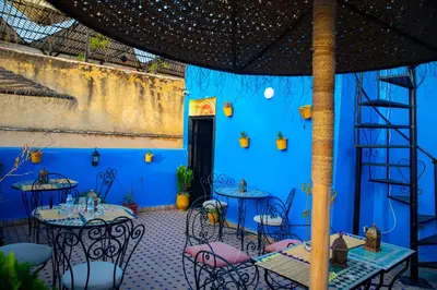 a blue room with tables and chairs in it at Riad LalaMoune in Fès