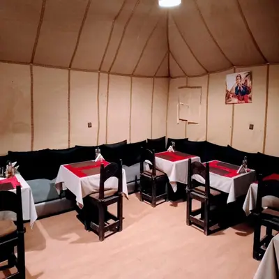 a room with tables and chairs in a tent at Merzouga Berber Camps in Merzouga