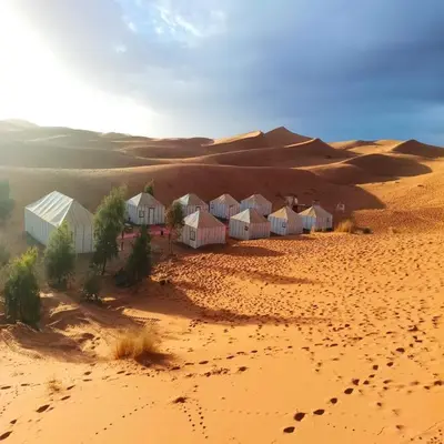 a desert with a row of houses in the sand at Merzouga Berber Camps in Merzouga