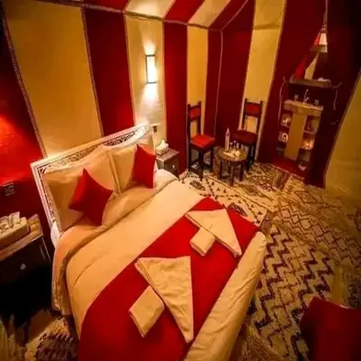 a bedroom with a large bed with red and white pillows at Merzouga Berber Camps in Merzouga