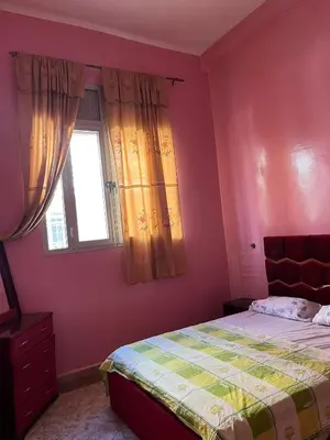 a bedroom with pink walls and a bed and a window at Belo appart bassatine in Meknès