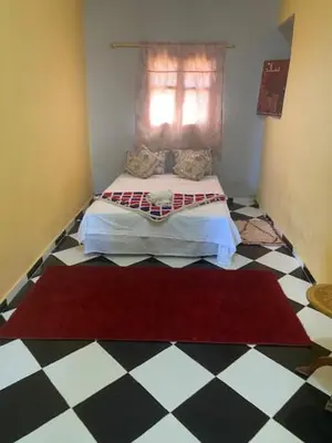 a bedroom with a bed and a checkered floor at Gite Cèdre Gouraud in Azrou