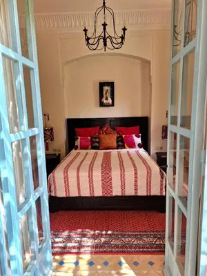 a bedroom with a large bed with red pillows at LA PORTE AU LION - Marrakech in Marrakech