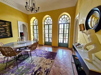a dining room with a table and chairs and windows at LA PORTE AU LION - Marrakech in Marrakech