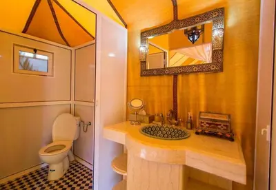 a bathroom with a toilet and a sink and a mirror at Sahara Elegance Camp in Merzouga