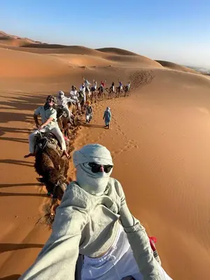 a group of people riding camels in the desert at Sahara Elegance Camp in Merzouga
