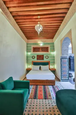 a bedroom with a bed and a couch and a rug at Riad Ridaya in Fès