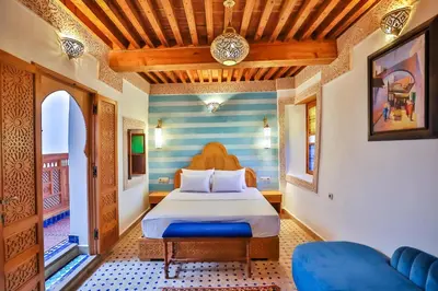 a bedroom with a bed with a blue and white striped wall at Riad Ridaya in Fès