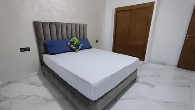 a bed in a white room with a wooden door at Coin vert in Fès