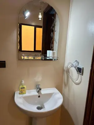 a bathroom with a white sink and a mirror at Jannat Résidence in Ouarzazate