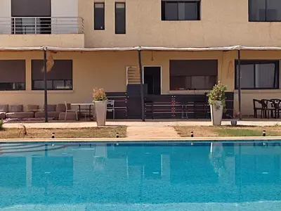 a swimming pool in front of a building at Lina Village in Al Hachlaf